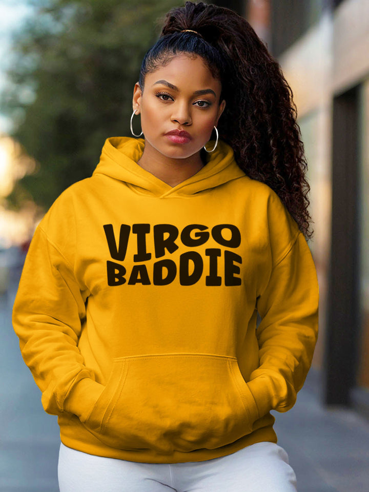 Woman wearing a gold color custom graphic hoodie with bold black text design artwork that reads “VIRGO BADDIE” in large, playful bubble style block letters. 